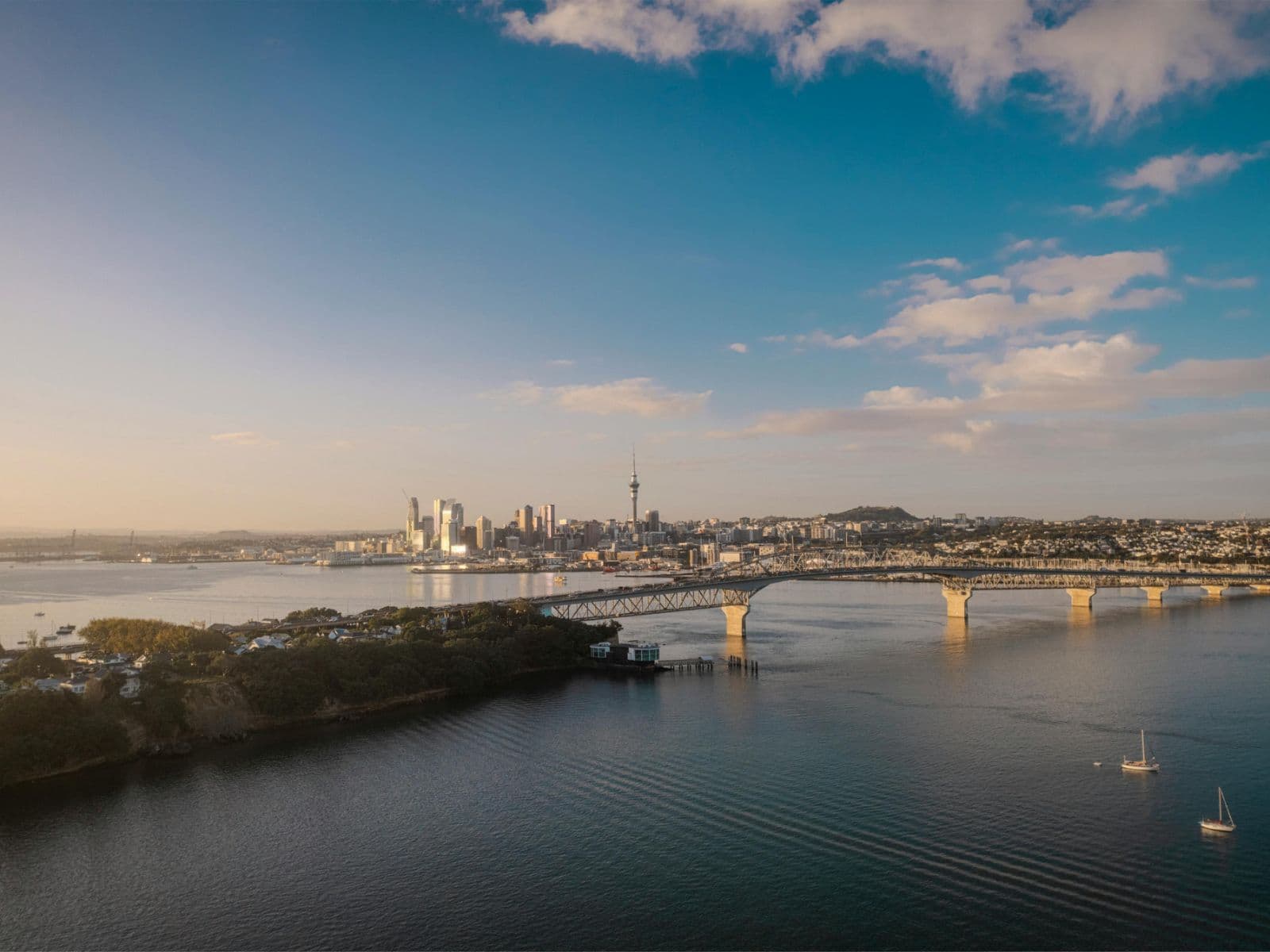 Auckland Harbour at dusk, with the Harbour Bridge and the city skyline seen from the North Shore