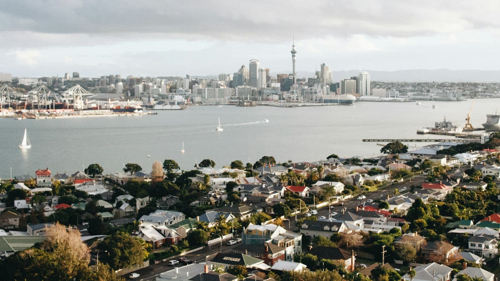 The Auckland harbour and city skyline seen over the rooftops of a suburb across the water