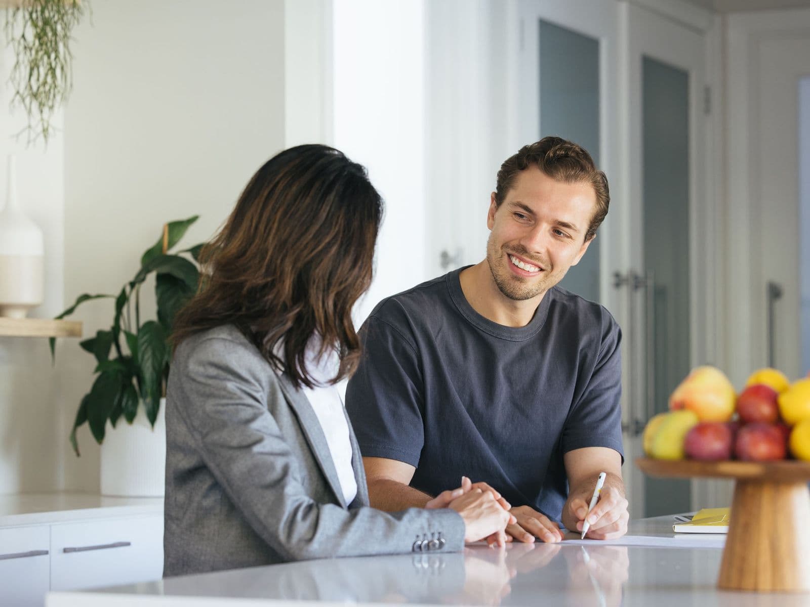 A property manager and a tenant talking at a kitchen bench in a bright home